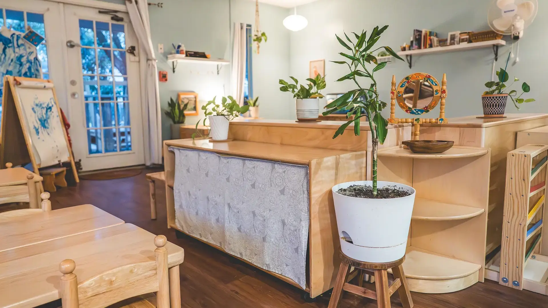 Montessori classroom with wooden shelving and a potted plant.
