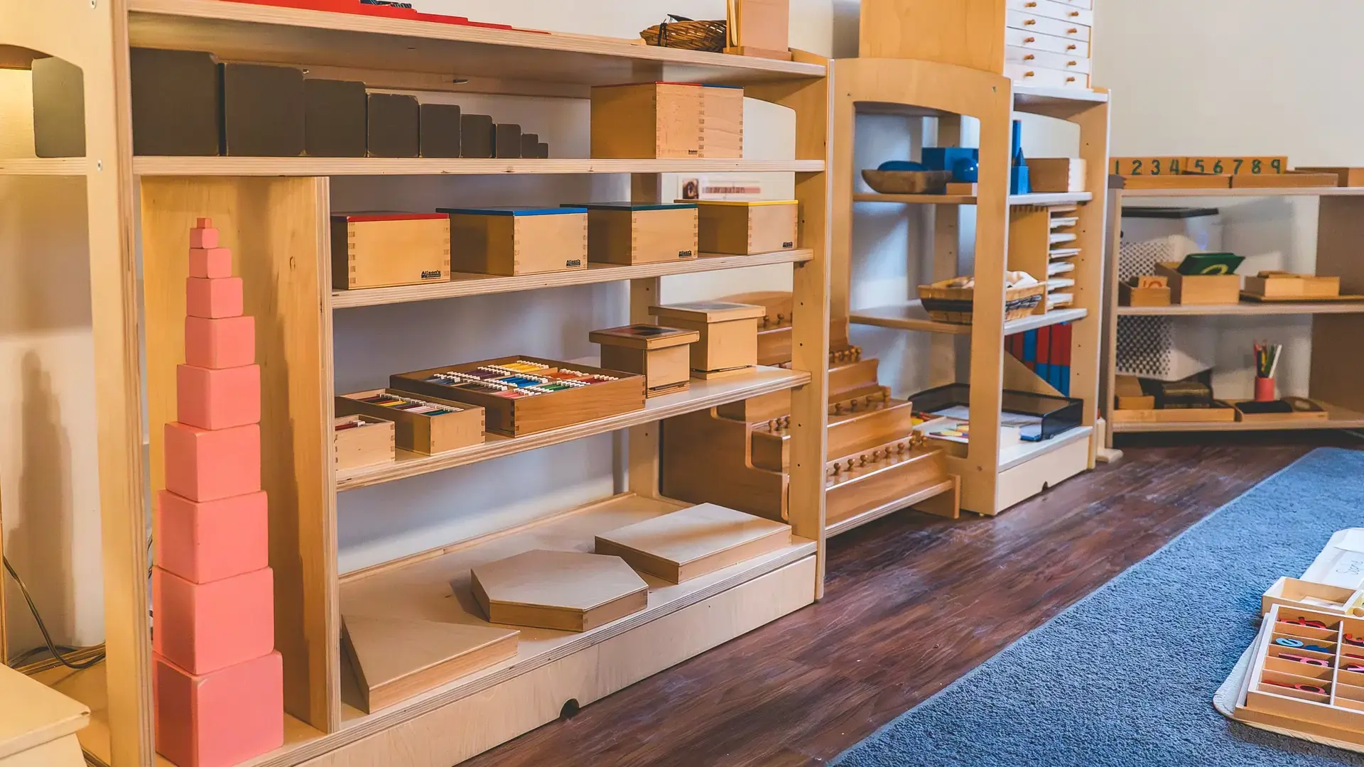 primary classroom shelves with Montessori materials, including a pink tower.