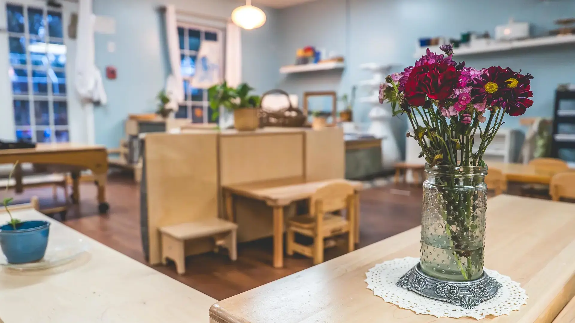 Montessori classroom with wooden tables and a flower centerpiece.