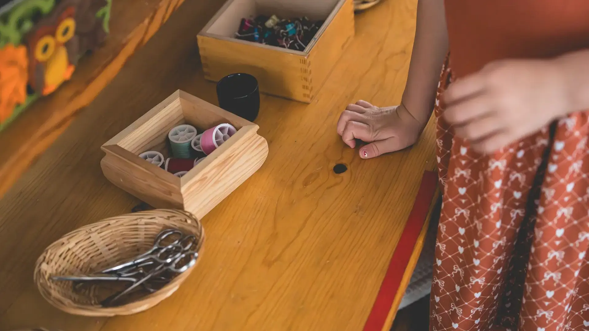 Young child in a primary classroom reaching for materials on a table with baskets.