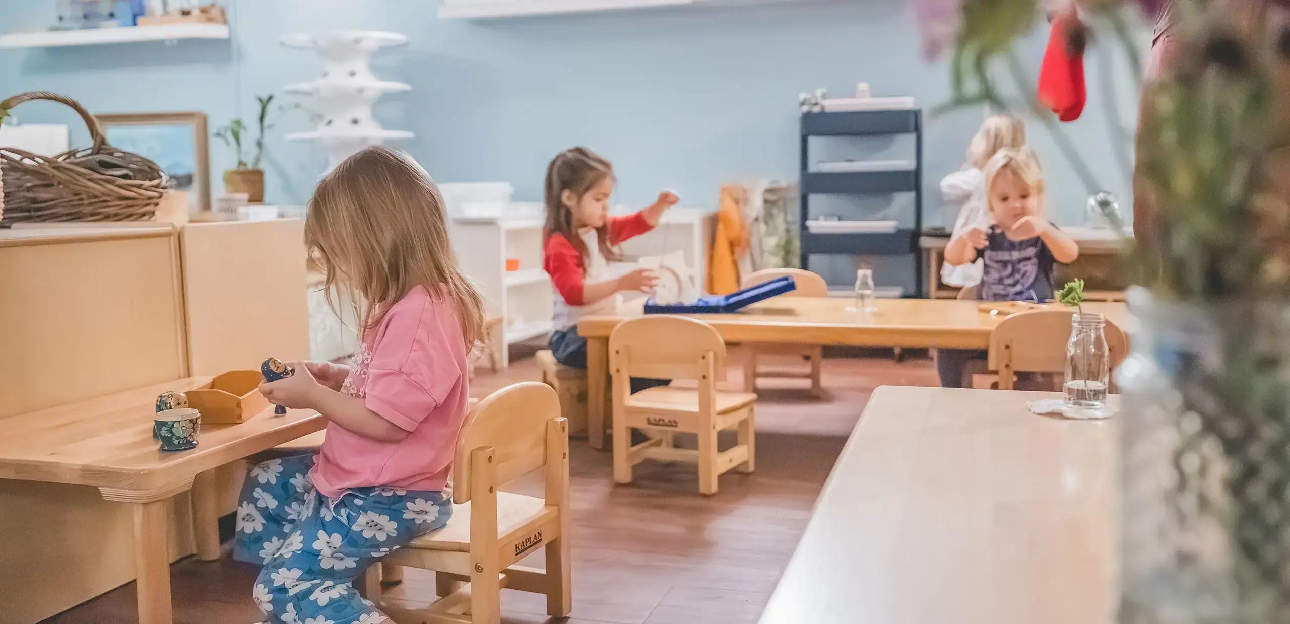 Young children working independently on individual activities throughout a Montessori classroom.